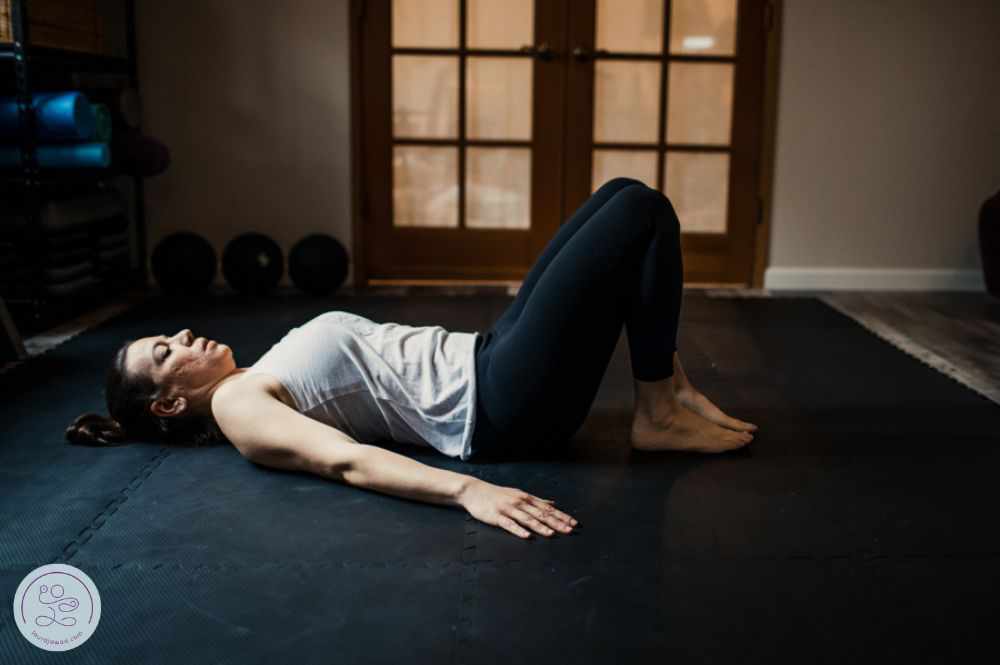 A postpartum mom lying on her back with knees bent, preparing for breathing exercises.