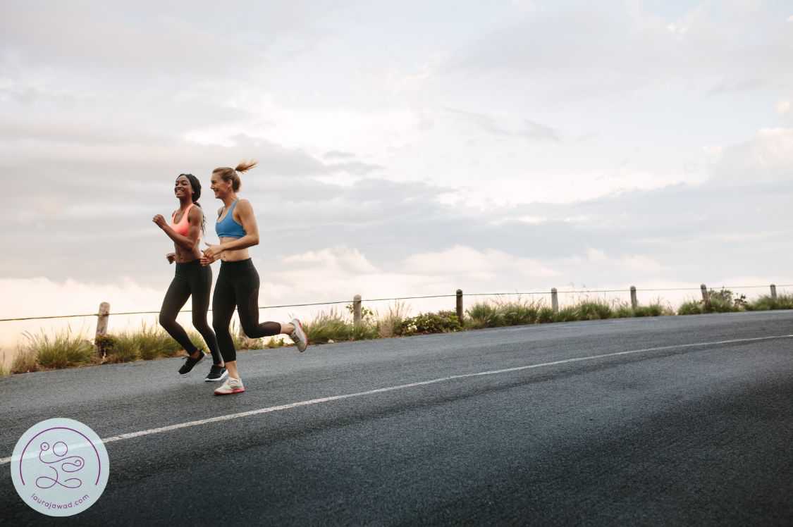 2 postpartum athletes running down an empty road.